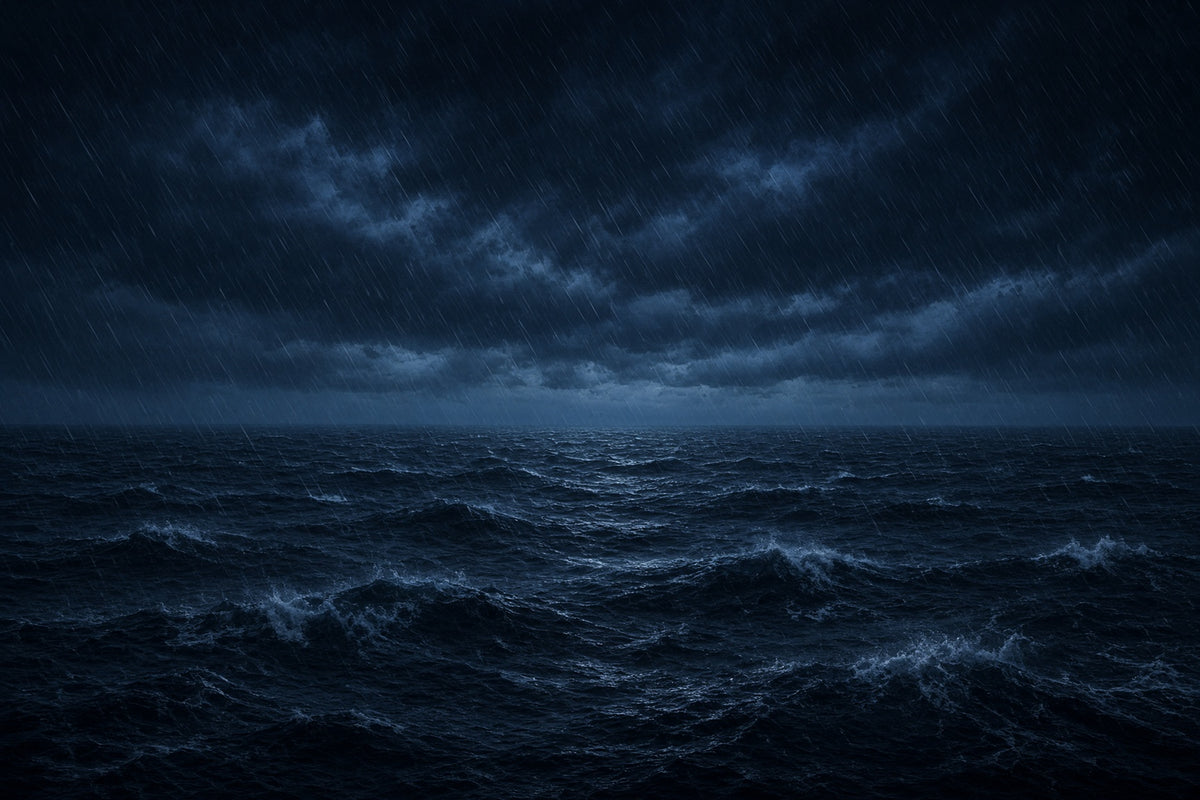 A dramatic stormy seascape at night with dark blue ocean waves, heavy rain, and a cloudy sky.
